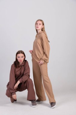Giysi kataloğu için stüdyoda kahverengi ve bej renkli günlük kıyafetlerle poz veren bir çift modaya uygun model. Sonbahar kadın modasının örnekleri. Boşluğu kopyala.