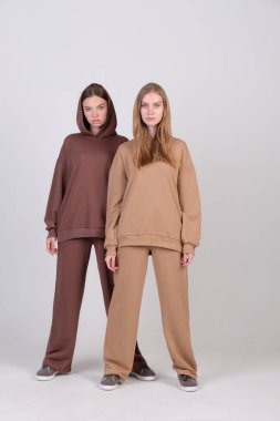 Giysi kataloğu için stüdyoda kahverengi ve bej renkli günlük kıyafetlerle poz veren bir çift modaya uygun model. Sonbahar kadın modasının örnekleri. Boşluğu kopyala.