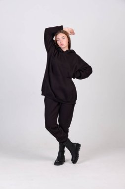 Moda mankeni tamamen siyah giyinmiş. Stüdyoda poz veriyor. Kitap ve kıyafet kataloğu için..