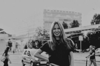 Büyük şehir arka planında gülümseyen güzel beyaz sarışın kadın. Mutlu bayan turistler. Siyah ve beyaz