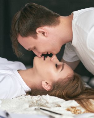 Ev ödevini bitirdikten sonra yatakta öpüşen serbest çalışan eşler. Heteroseksüel çiftte şefkat.