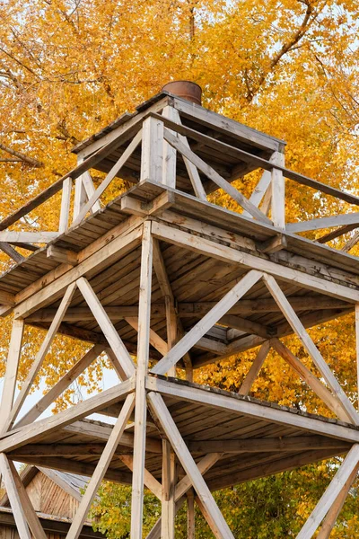 old wooden observation tower in camp. Yellow autumn trees on background. Selective focus.