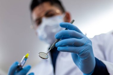 Ağız aynası tutan tanınmayan erkek dişçi.