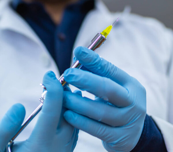 Hands of a dentist holding an anesthesia syringe