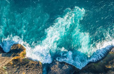 Endonezya, Bali 'deki Nusa Penida adasının kayalık kıyıları, kumsalları, gel-git havuzları ve uçurumlarından oluşan güzel manzaralı bir manzara. Fırtınalı dalgalar, deniz suyu ve güneşli bir gün.. 