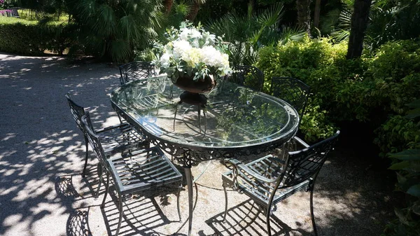 Masa arkaplanı ve ortasında çiçekler olan bahçe sandalyeleri