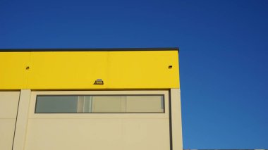 Mavi arka planda endüstriyel yapı cephesi ve çatı