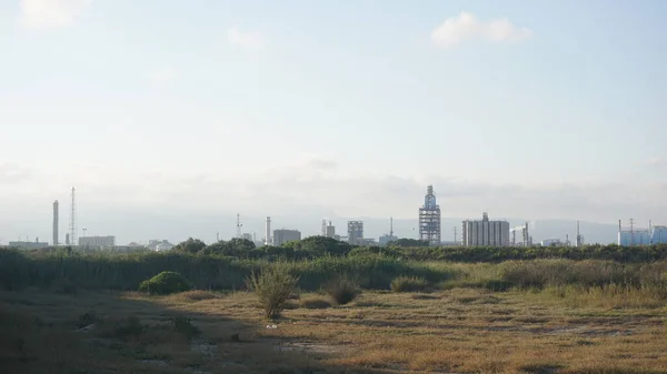 industrial skyline over green grass field