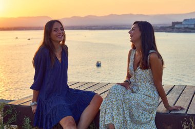 Deniz kenarında gün batımında iki genç kadın