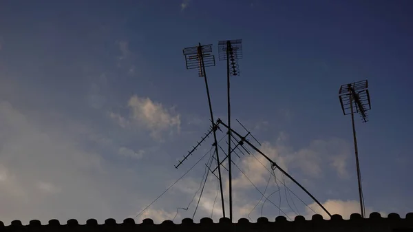 silhouette of television antennas on a roof