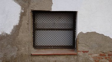 Bozulmuş duvar arkaplanına karşı ızgaralı pencere