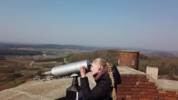 Vonzó női utazó távcsövet használ, hogy körülnézzen a völgyben a régi vár közelében — Stock videók