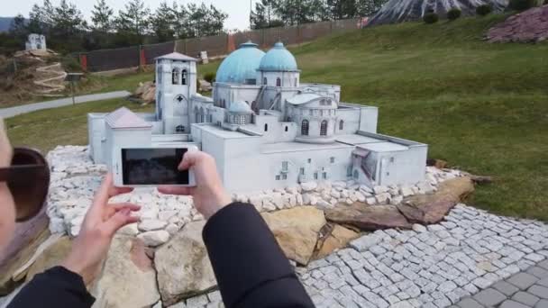 Donna scatta una foto vicino a un edificio in miniatura in stile arabo orientale. Parco delle Miniature. — Video Stock