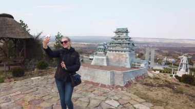 Kız, minyatür bir Çin pagodasının yanında selfie çekiyor. Minyatürler Parkı.