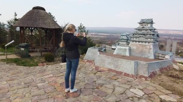 Femme prend une photo près d'une pagode chinoise miniature japonaise. Parc des Miniatures. — Video