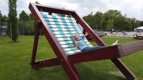 Žena leží na velmi velkém lehátku v parku. — Stock video