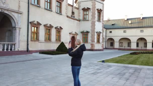 Дівчина-турист робить фотографію палацу на старій площі — стокове відео
