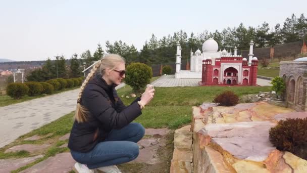Kız, Arap doğu tarzında minyatür bir binanın yakınında fotoğraf çekiyor. Minyatürler Parkı. — Stok video