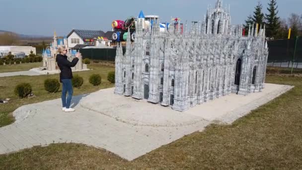 Femme fait une photo à pied près d'un modèle miniature de l'ancienne cathédrale de Milan, Italie. Parc des Miniatures. — Video