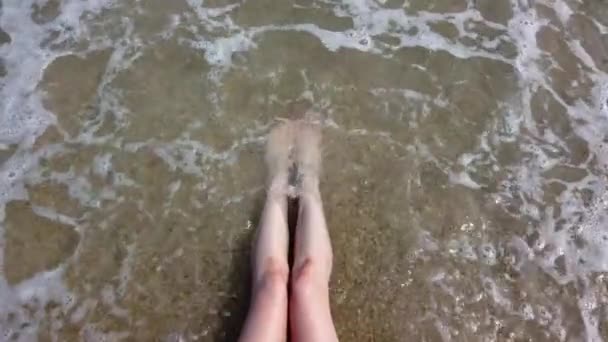 El agua de mar lava las piernas femeninas en la playa — Vídeo de stock