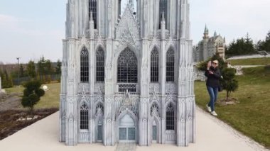 Kadın Avrupa 'daki eski Katedral' in minyatür bir maketinin yanında yürürken fotoğraf çekiyor. Minyatürler Parkı.