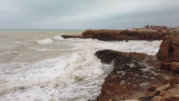 Das Meerwasser bricht an Felsen. Starke schäumende Wellen des Ozeans wälzen sich an der felsigen Küste der Insel. — Stockvideo