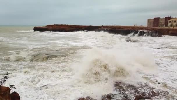 Movimento lento de uma forte e poderosa onda do mar batendo contra uma costa rochosa com grandes rochas. 4K — Vídeo de Stock