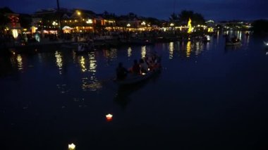 Yüzen fenerler ve teknelerle gece nehri manzarası. Hoi An, Vietnam 4K