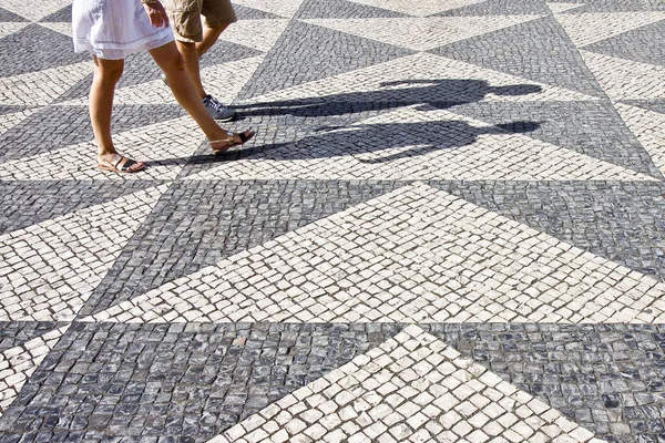 Two people walking in a typical Portuguese street paved in little stone - image with copy space