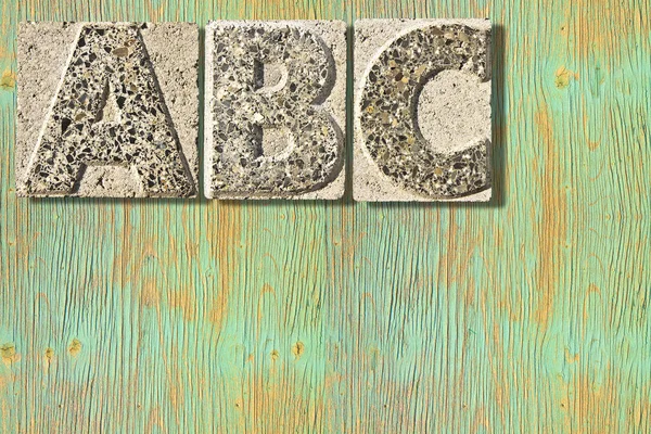 Letter A-B-C carved in a concrete block over a wooden background - concept image with copy spaceConcept image with copy space on wooden background