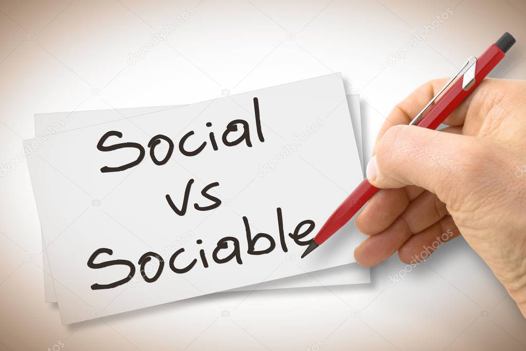Hand writing Social Vs Sociable with a pencil on a blank sheet - concept image