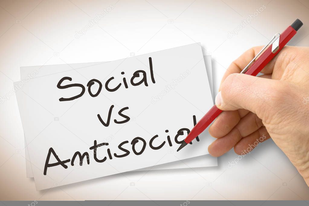 Hand writing Social Vs Antisocial with a pencil on a blank sheet - concept image