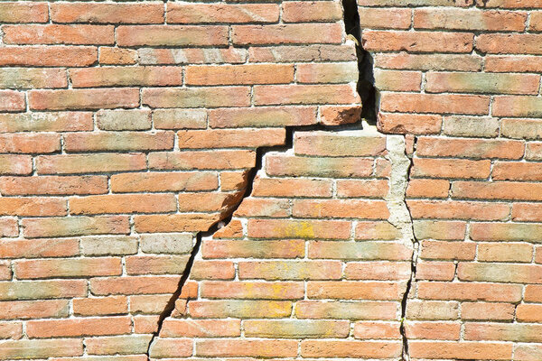 Old brick wall cracked and damaged - wall with diagonal crack