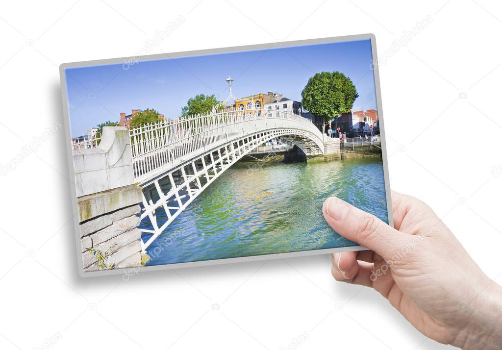 A female hand holding an postcard about the most famous bridge in Dublin called 