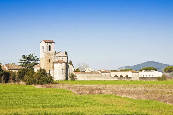 Toscana típica igreja romanesca cercada por um campo perto de um c — Fotografia de Stock