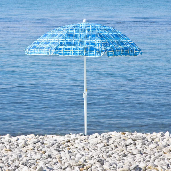 Guarda-chuva colorido isolado em uma praia de pequenas pedras — Fotografia de Stock