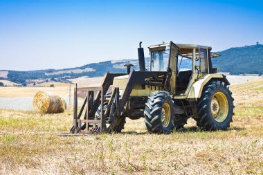 Eski traktör arka plan üzerinde yuvarlak balya bir tepenin durdu