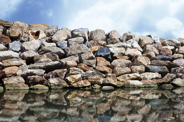 Rock wall protection from the waves agaist a a a blue sky — стоковое фото