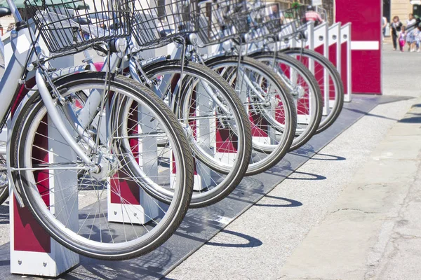 Cinque biciclette a noleggio parcheggiate in una strada italiana - immagine con poliziotto — Foto Stock