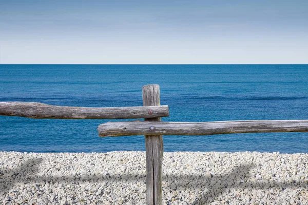 Barreira de madeira construída com postes contra um mar azul - conceito ima — Fotografia de Stock