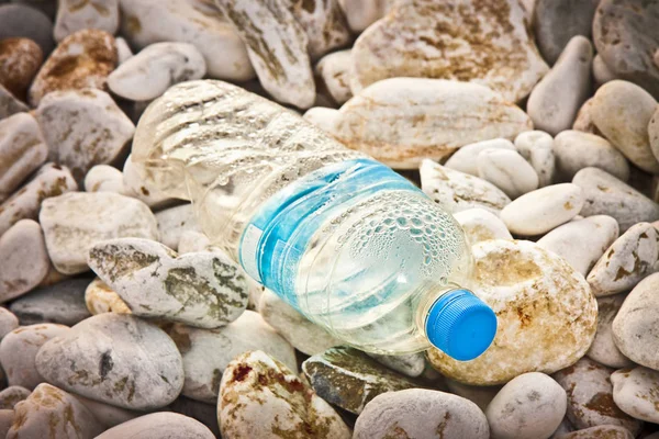 Lege blauwe plastic fles met blauwe dop op gravel Beach — Stockfoto