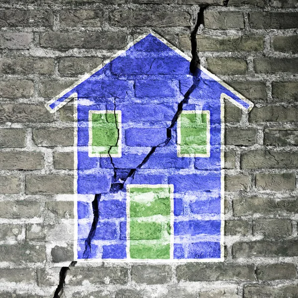 Cracked brick wall with a blue house drawn on it