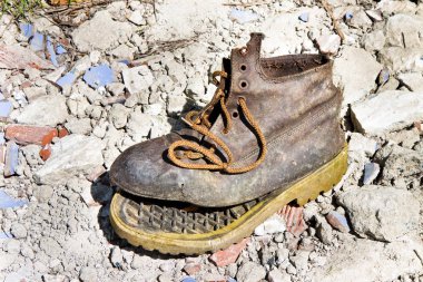 Old broken boot abandoned in a rubble background clipart