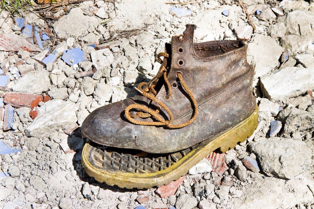Old broken boot abandoned in a rubble background