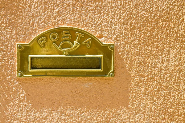 Brass mail box built into a colored plaster wall