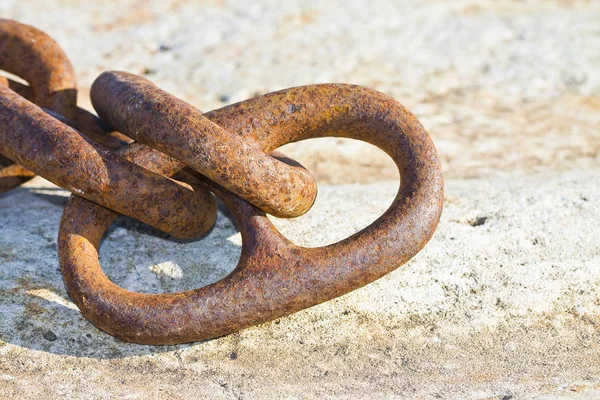 Detalhe de uma cadeia de metal enferrujado velho ancorado a um bloco de concreto — Fotografia de Stock