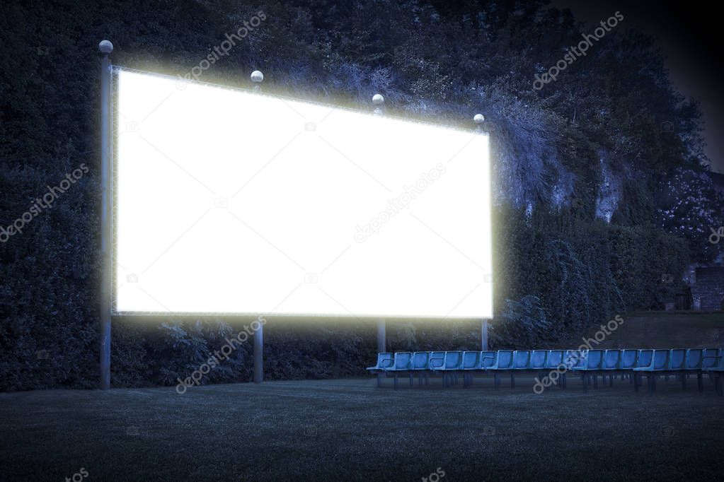 Outdoor cinema with chairs and white projection screen in nature