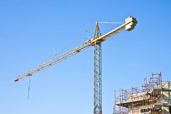 Tower crane in a blue background with metal scaffolding to work — Stock Photo, Image