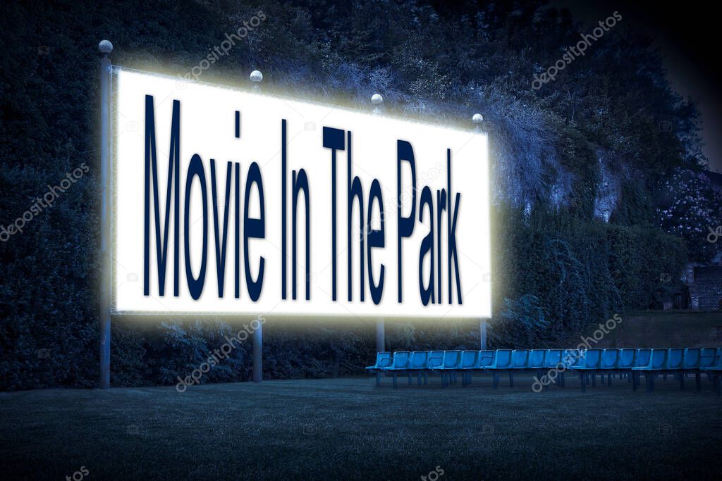 Outdoor cinema with chairs and white projection screen with 'Movie In The Park' text written on it