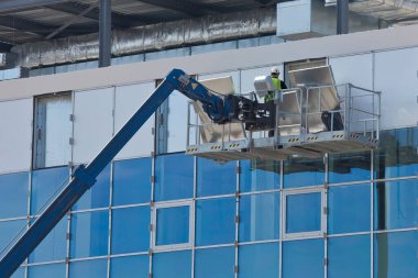 MODERN Bina Yüzündeki Exterior Panelleri 'nin ELEKTİM Platformu' nda çalışan işçi, ofis binasına kaplama yapmak için güvenlik donanımı takıyor.